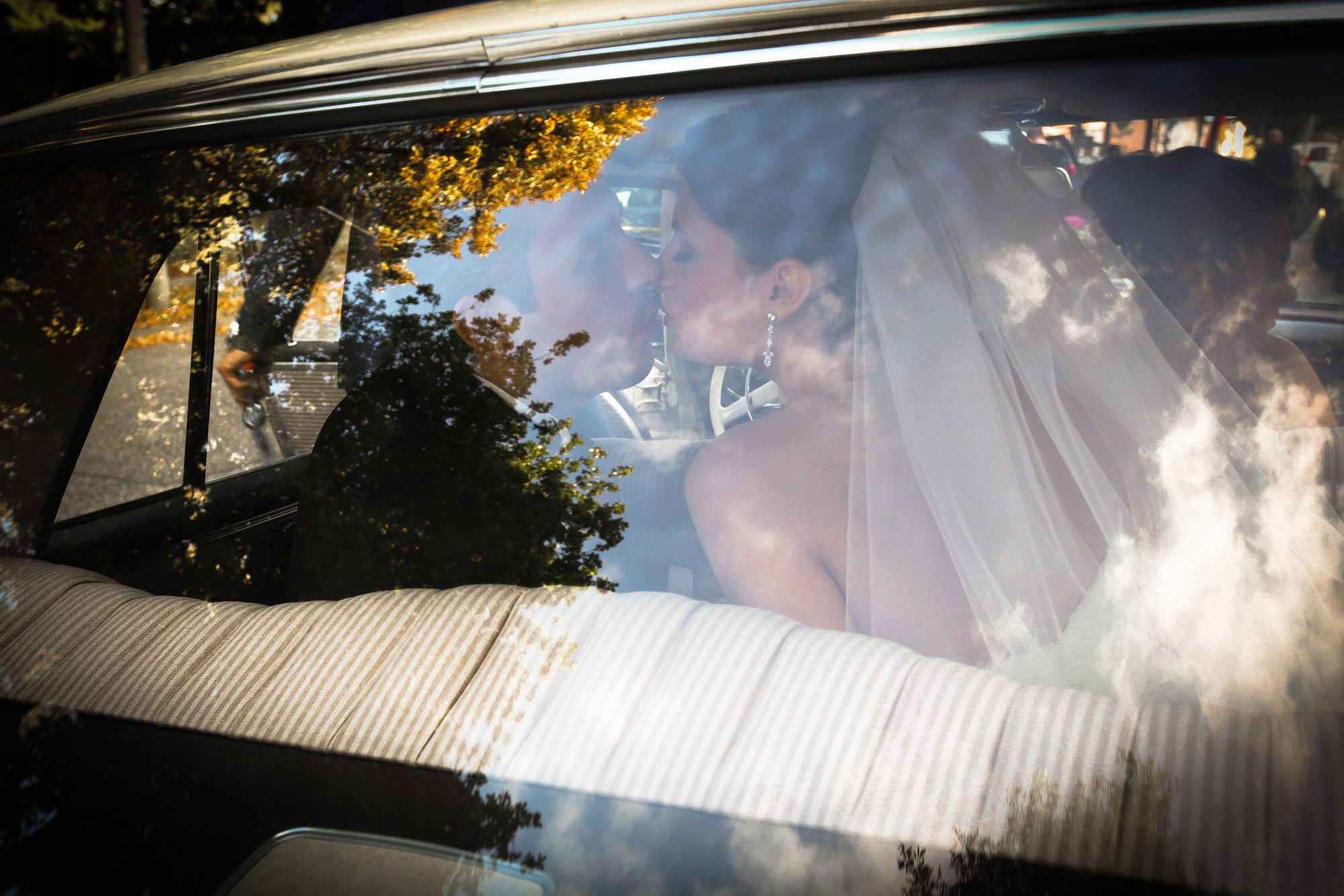 Brautpaar küsst sich durch die Fensterscheibe eines Hochzeitsautos, Hochzeitsfotograf Hamburg