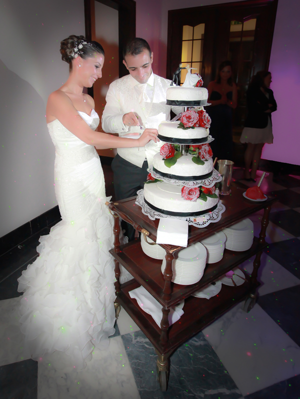 Brautpaar schneidet gemeinsam die dreistöckige Hochzeitstorte an