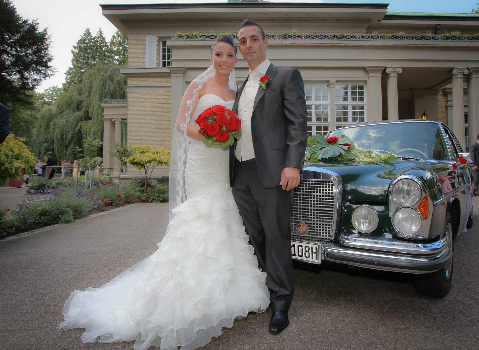 Brautpaar steht vor historischer Villa neben grünem Oldtimer mit Blumenschmuck, Hochzeitsfotograf Hamburg