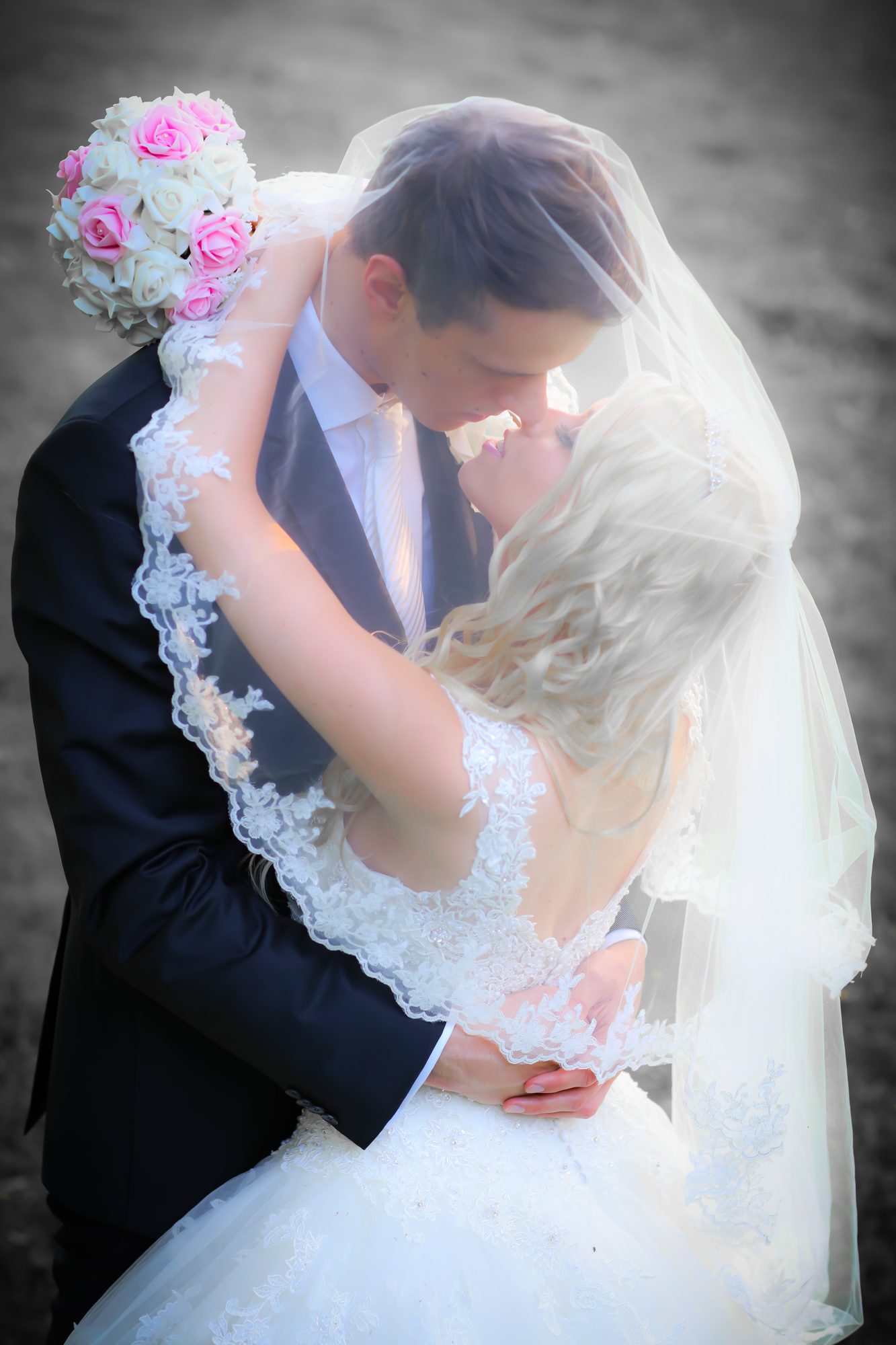 Brautpaar umarmt sich innig beim Kuss, Braut trägt Schleier und hält Rosenstrauß, Hochzeitsfotograf Hamburg