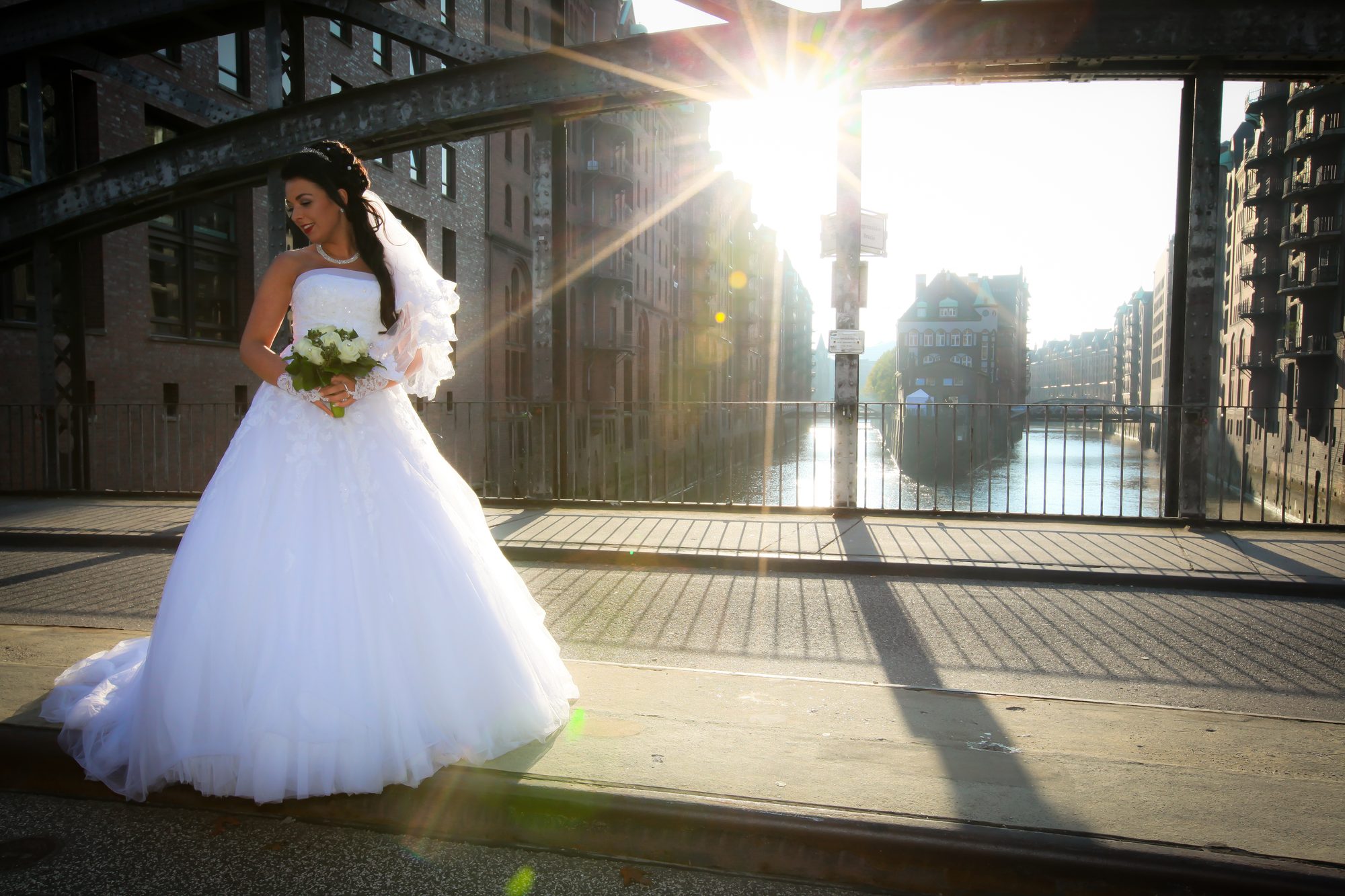 Braut mit Brautstrauß auf einer Brücke in der Speicherstadt im Gegenlicht, Hochzeitsfotograf Hamburg